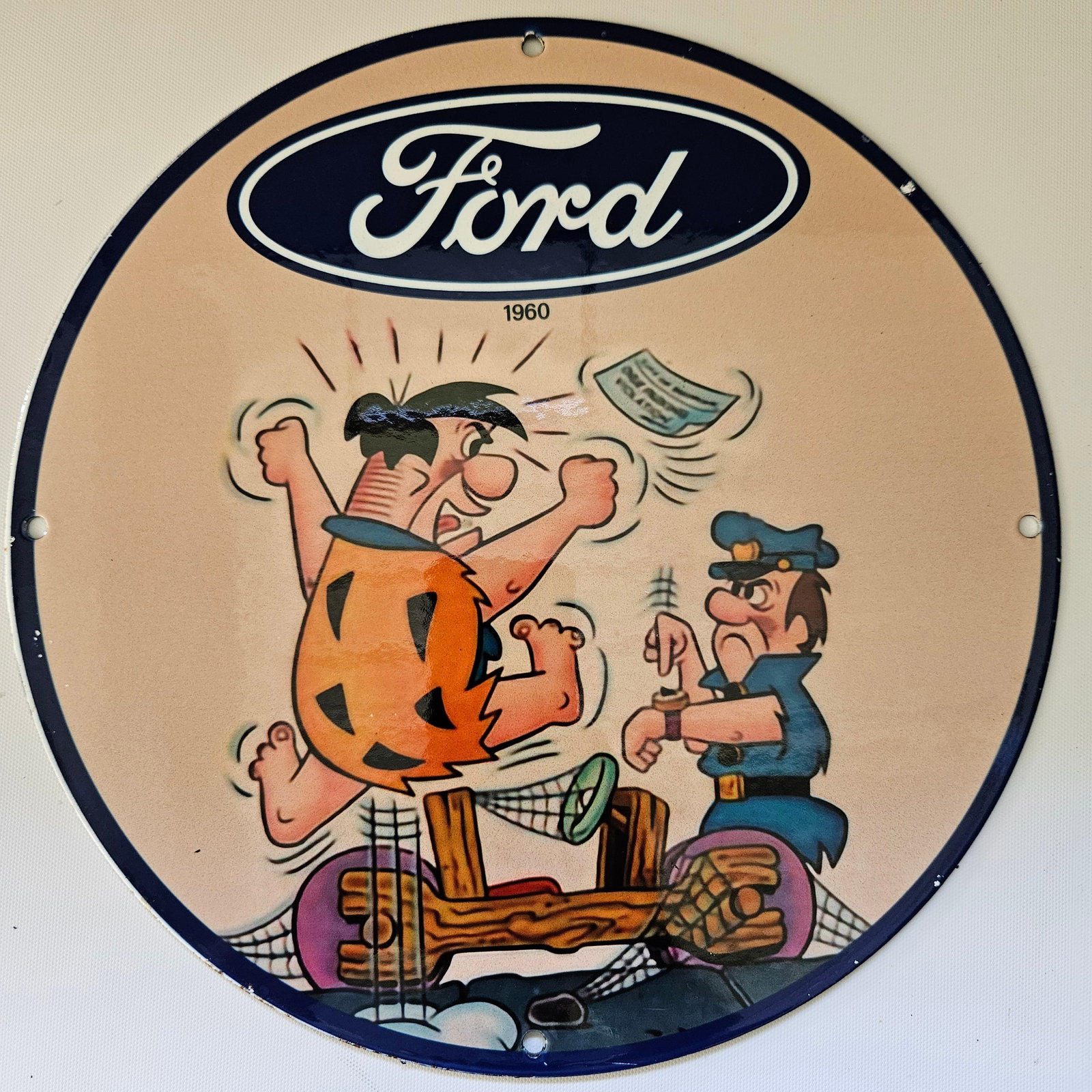 1960 FORD AUTOMOBILE "FLINTSTONES" GAS OIL GARAGE MAN CAVE PORCELAIN SIGN: The 1960 Ford automobile "Flintstones" sign, measuring approximately 12 inches in diameter, is a nostalgic piece of advertising history, evoking the charm of yesteryears. Featuring vibrant colors and 