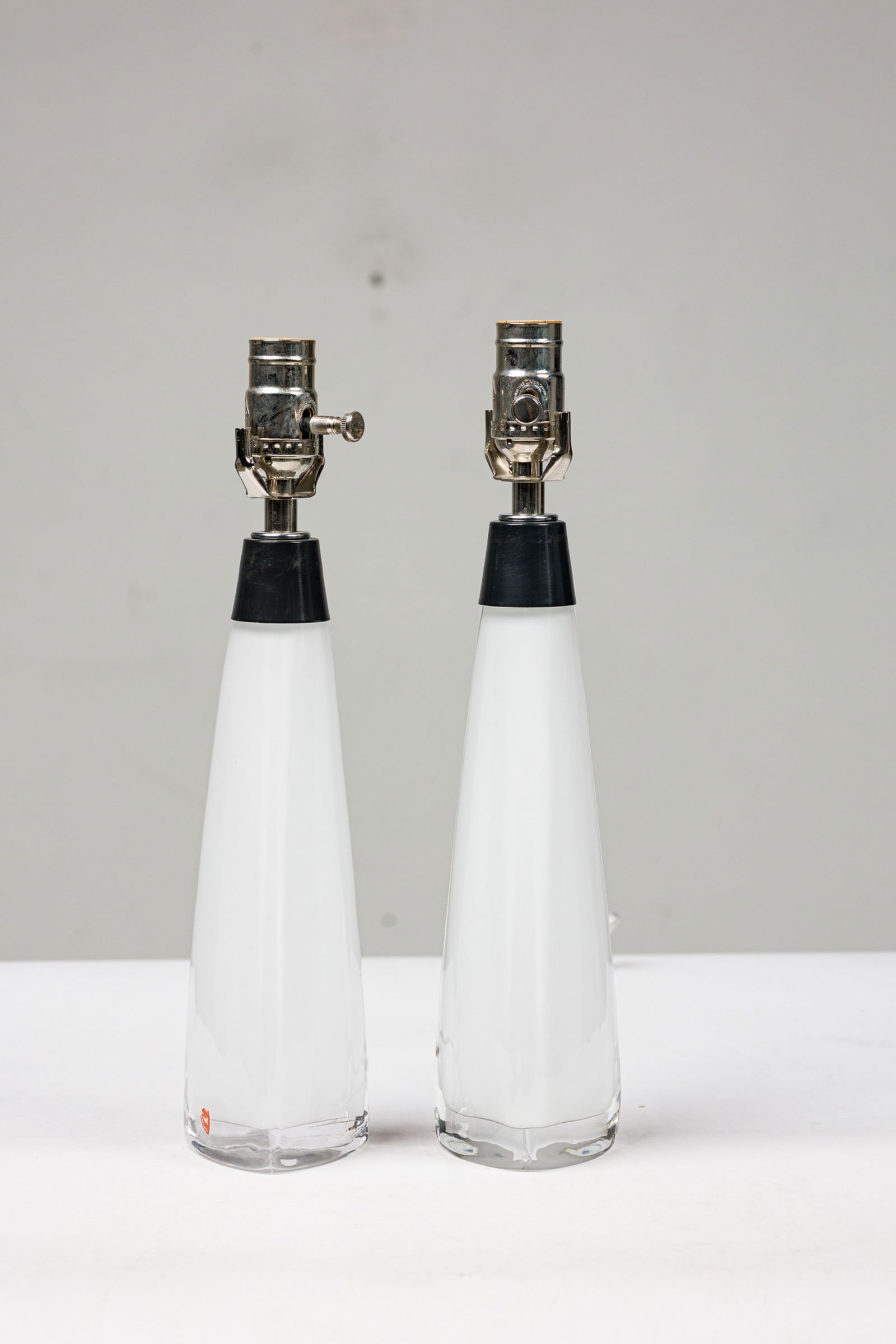 Carl Fagerlund For Orrefors, (2) White Glass Lamps: c. 1960s, Sweden, triangular white crystal base with a weighted clear crystal bottom, wired with upright sockets, labeled "Orrefors", 15"h x 4"w x 4"d (base) Provenance: From a SIngle-Owner Collection