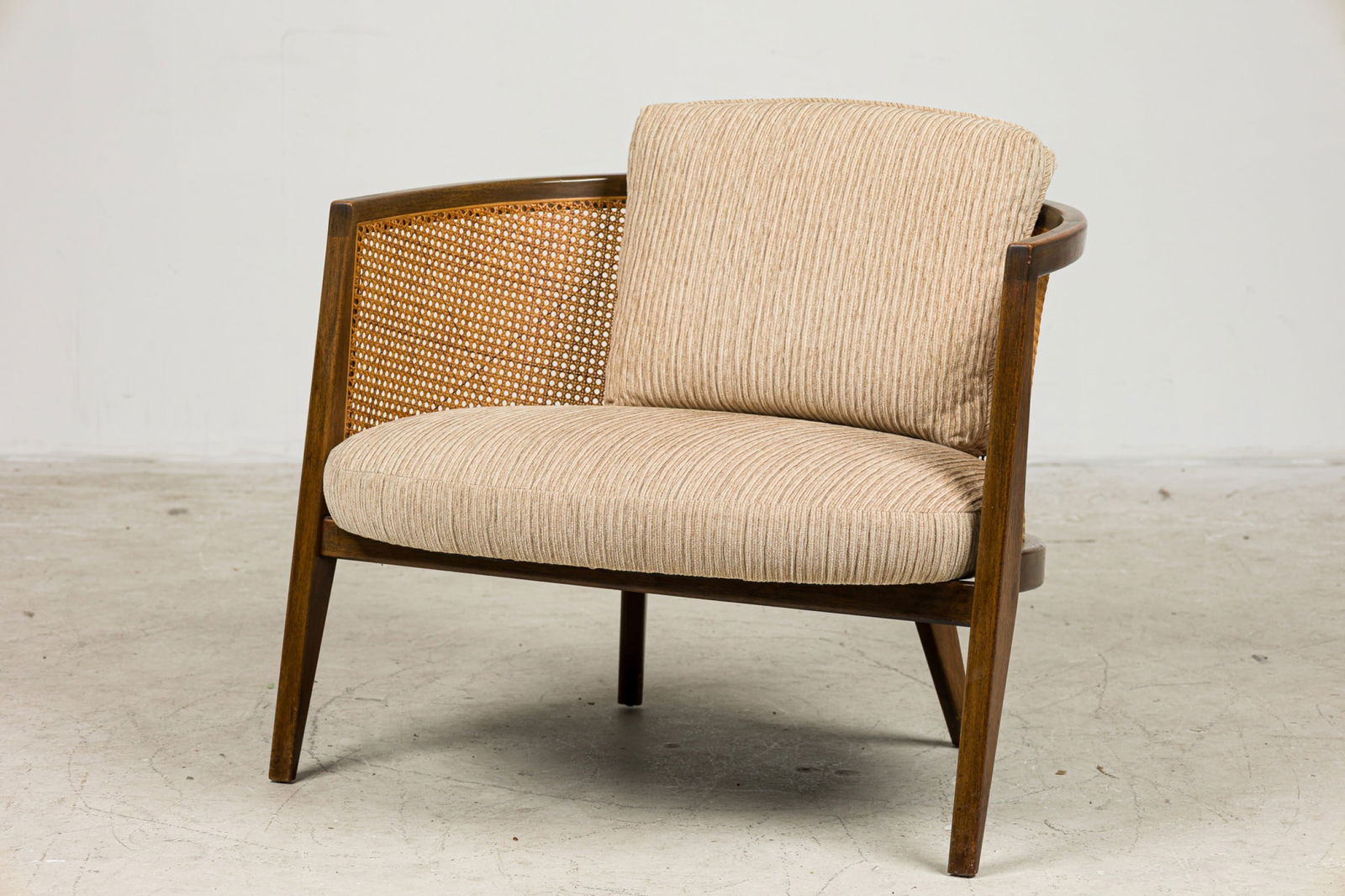 Harvey Probber, Cane-Back Tub Chair: c. 1960, USA, brown stain mahogany, woven rattan, the seat and back cushion upholstered tan channeled wool, 24"h x 31"w x 29"d, 15"h (to seat) Provenance: Property from a Tommi Parzinger Furnished Hom