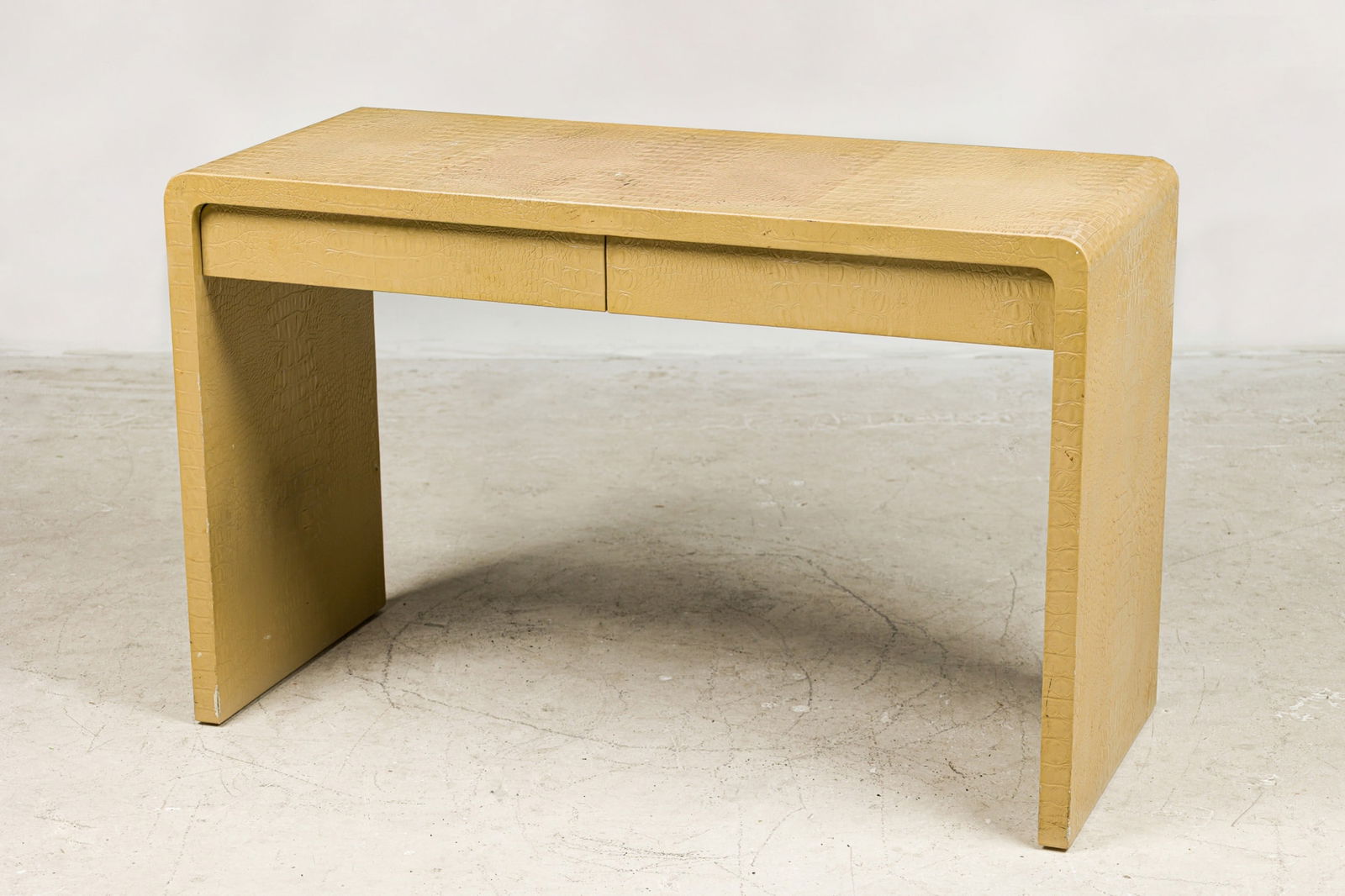 Karl Springer, Alligator Skin Waterfall Desk: c. 1970s, alligator textured leather, with two frieze drawers, functions as a small desk or console table, 30"h x 48"w x 20"d Provenance: Property from a Tommi Parzinger Furnished Home, Westfield NJ