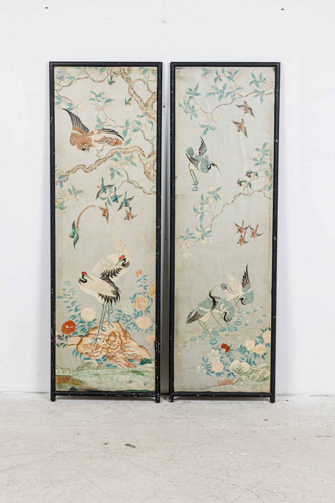 Pair Chinoiserie gouache painted panels: 19th/20th c., polychrome paint on silver ground, decorated with cranes and other birds, flowering prunus and chrysanthemum, in black painted faux bamboo frame, possibly by Gracie Studio, 68"h x 2