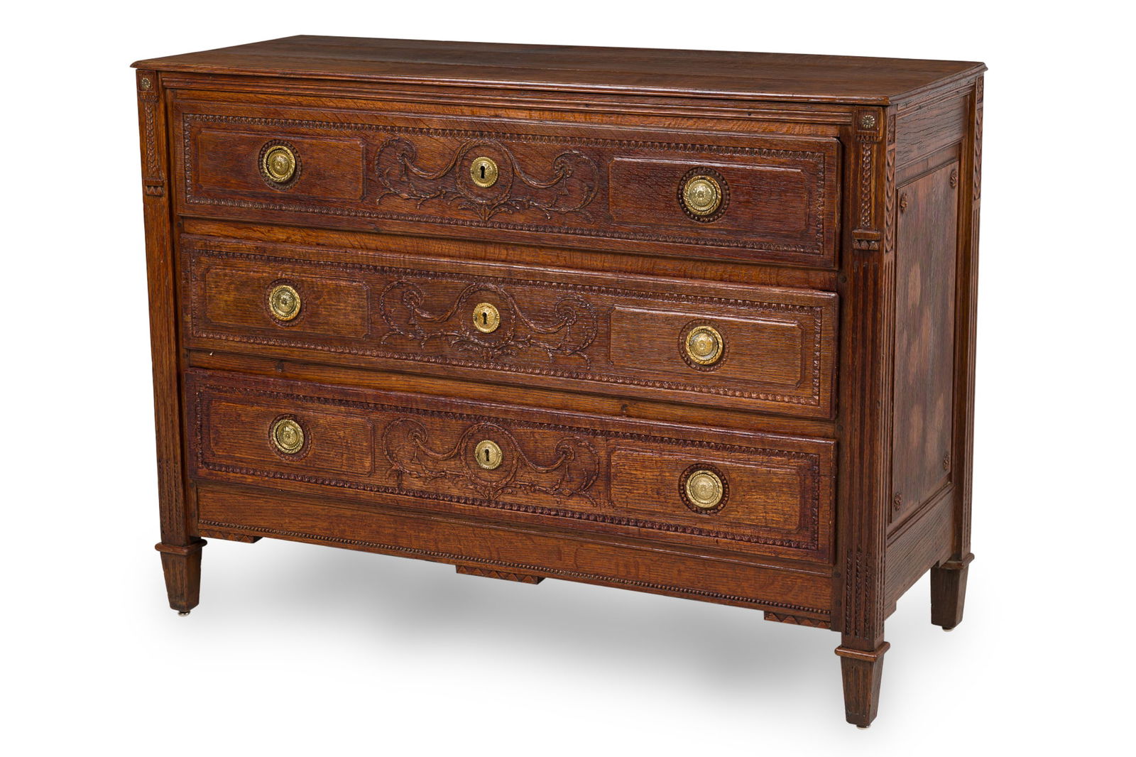 Louis XV French Provincial Oak 3-Drawer Chest: 18th c., France, dark stained oak, brass ring pulls, the drawer fronts carved with wreath and border carved embellishments, flanked by fluted carved pilasters and resting on four square tapered legs,