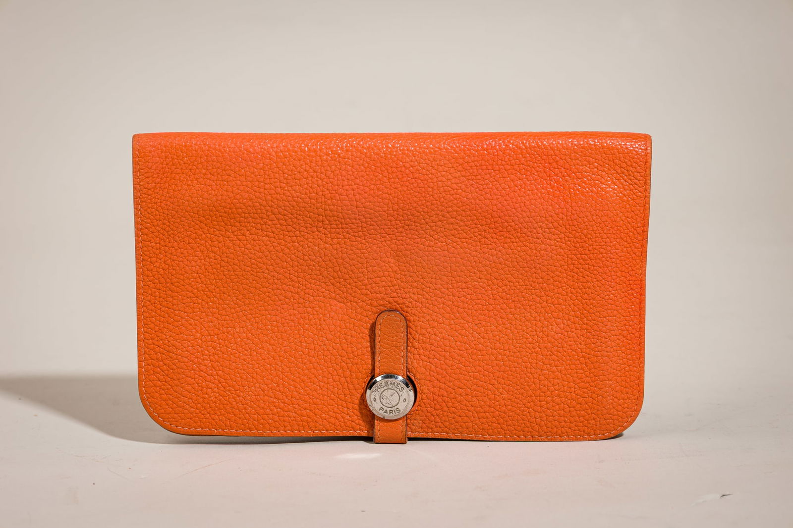 Hermes Dogon GM Wallet: Brand: HermesModel: DogonMaterial: LeatherColor: Togo orangeDate Code: EApprox. Dimensions: 7.2" W x 4.2" HFeatures: Coin purse, multiple slotsCondition: In very good pre-owned condition