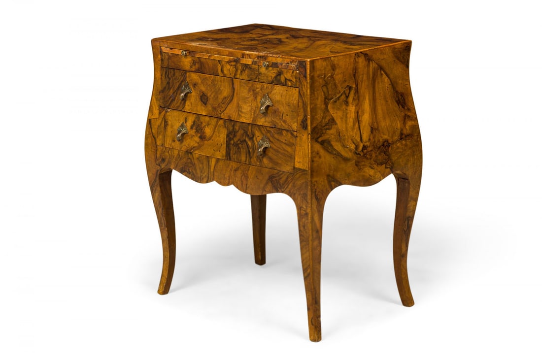 Italian Mid-Century burlwood two drawer commode: 20th c., Italy, figured mahogany burl veneer, patinated brass pulls, the rectangular top over pull out surface and two stacked drawers, serpentine skirt, raised on four saber legs, 27" h x 22.25"w x 1