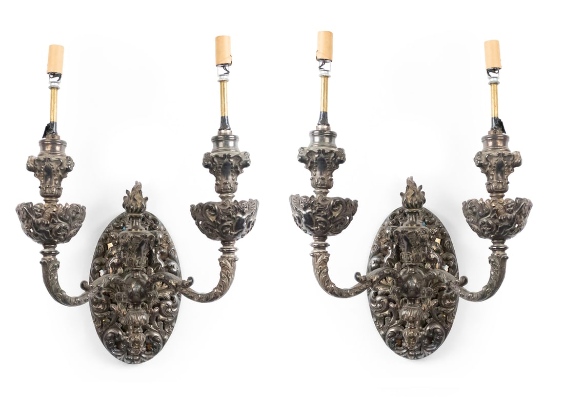 Pair of French Second Empire silver plate two-arm sconces: late 19th c., France, Baroque design with foliate scrolls and filigree, a flame finial top, cupid head ornaments, 11"h x 12"w x 8"d