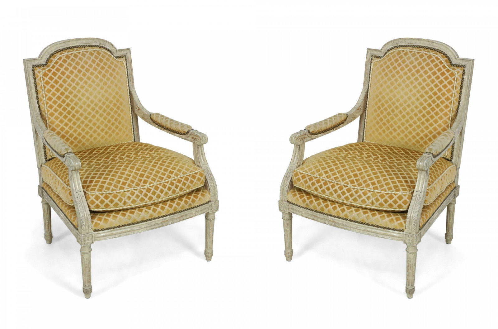 Pair of Louis XVI-Style upholstered fauteuils: 19/20th Century, France, distressed grey painted frames, the padded back and seat upholstered in a gold diamond-patterned upholstery, raised on round fluted legs, 38" h x 27"w x 28"d