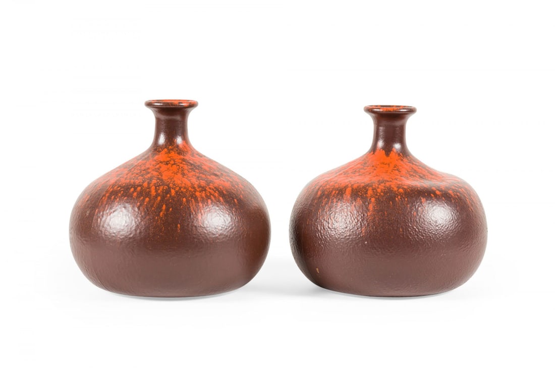 Pair West German style speckled ceramic cabinet vases: mid-20th c., likely Germany, burnt red glaze with bright orange splatter round shoulder and neck, the bulbous body tapering to a thin neck with a flared opening, paper tag to underside, 5.75" h x 5.5"