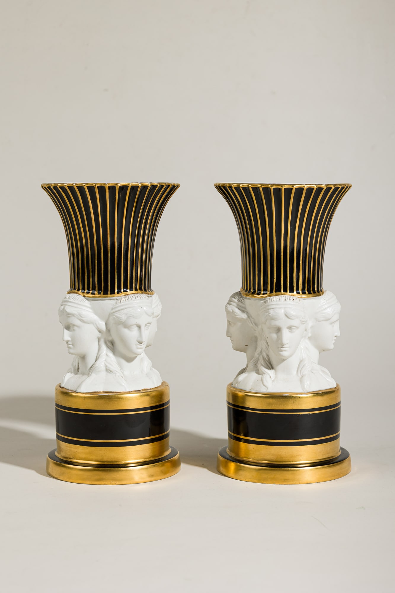Pair Sevres style Old Paris Porcelain parcel gilt and bisque vases: late 19th c., France, black enamel and parcel gilt porcelain, decorated with three Neoclassical female busts, blue underglaze crown mark to underside, 12"h x 5.5"dia Provenance: Pr