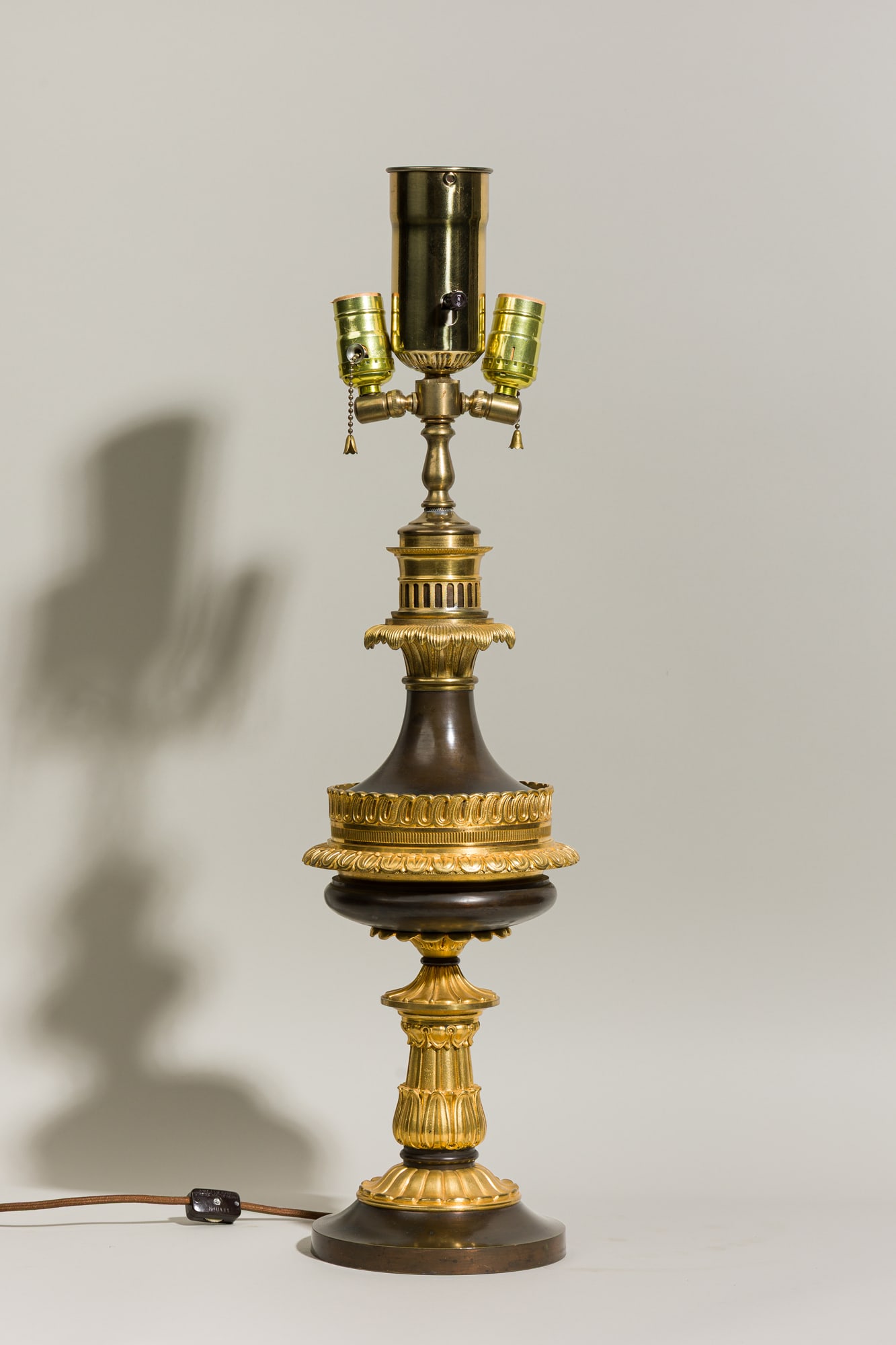 Napoleon III bronze and ormolu electrified oil table lamp: c. 1860s, France, adapted from an oil lamp in the Louis XVI taste, dark patinated bronze, gilt bronze elements cast with lotus fronds and drapery swags, wired with three upward pointing electrifi