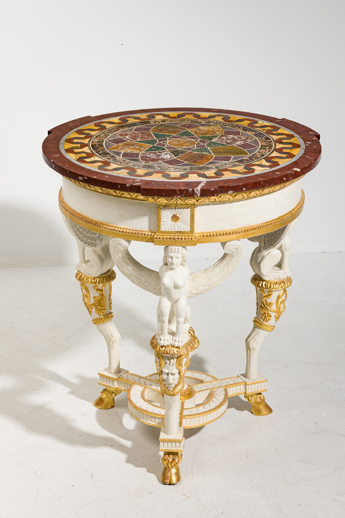 Fine early 18th c. Italian Neoclassical pietra dura specimen table: first quarter 19th c., Italy, mixed marble and alabaster mosaic top, on a gilt and white-painted neoclassical frieze raised on three carved winged sphinx-shaped supports, joined at the 