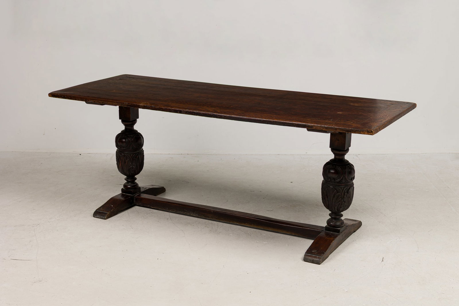 English Jacobean style oak refectory table, ex-Sotheby's: 19th/20th c., England, the rectangular top on two acanthus carved baluster trestles joined by stretcher, Sotheby's NY green label to underside, 30"h x 78"l x 30"w Provenance: Proper