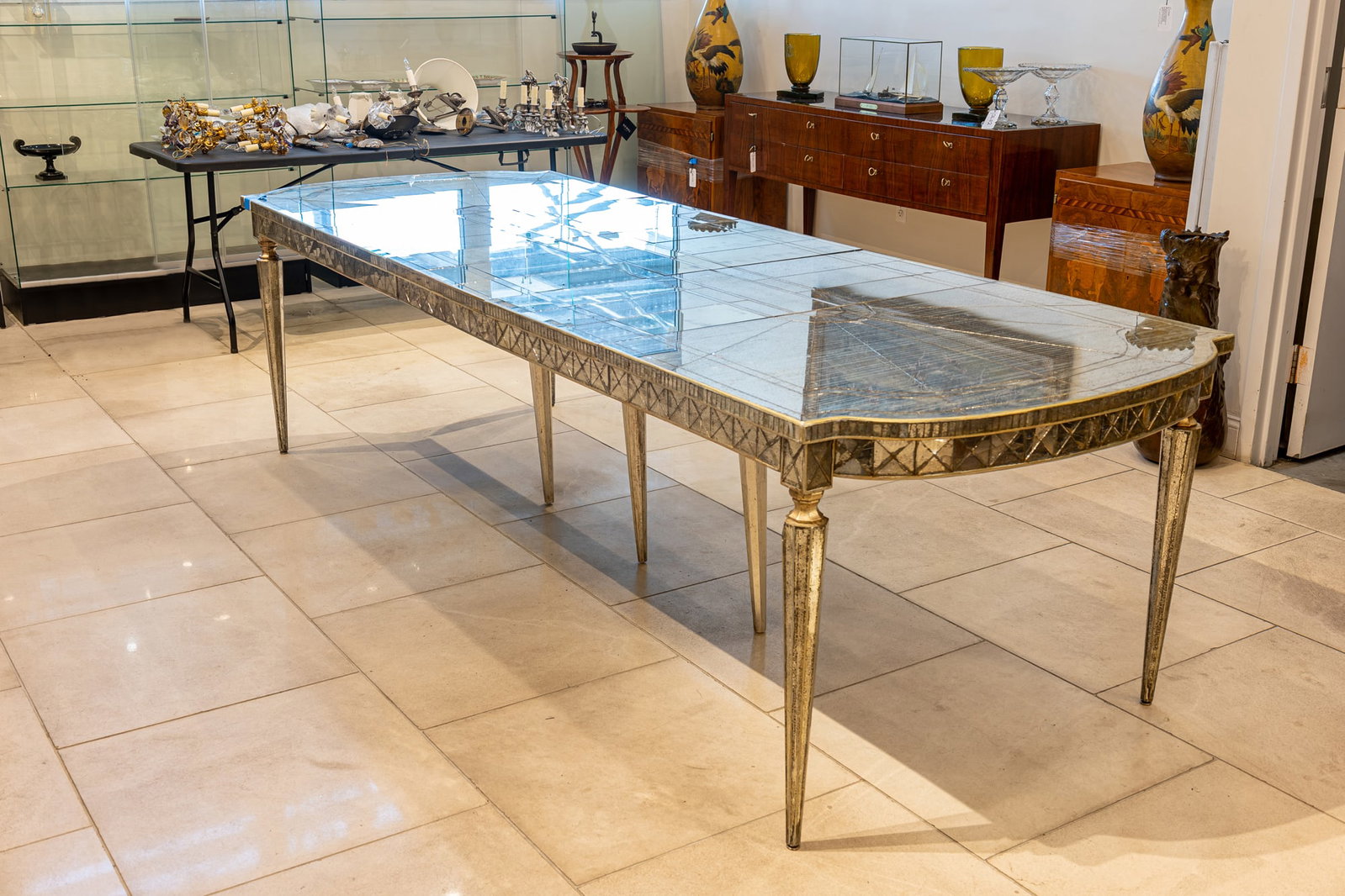 Neoclassical style, mirrored glass dining table: c. 1940s, USA, long oval shaped, distressed foxed finished mirrors, with four leaves, resting on four detachable wooden tapered legs with a silver finish, 30.75"h x 114.5"l x 40.5"w&nbs