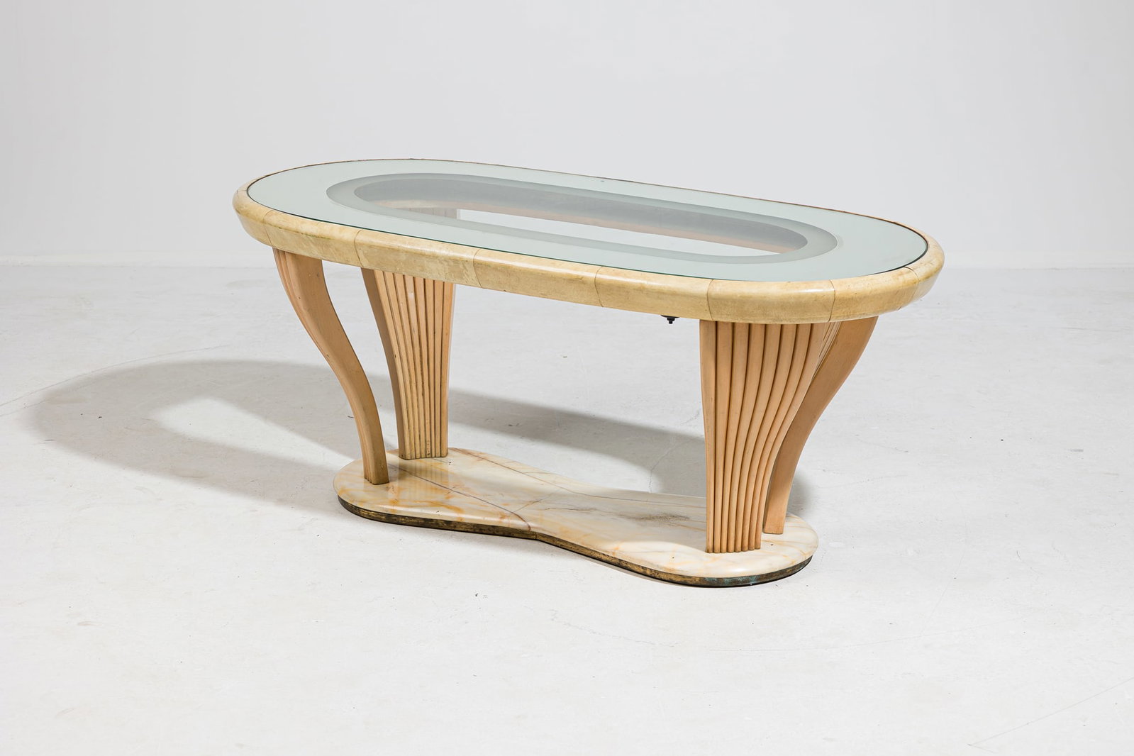 Vittorio Dassi, Italian Modern parchment clad coffee table: c. 1940s, Italy, mirror banded glass top, inset on a parchment clad frame, resting on four fluted sycamore supports on an onyx base, 21"h x 46.5"l x 23"w Provenance: Prop