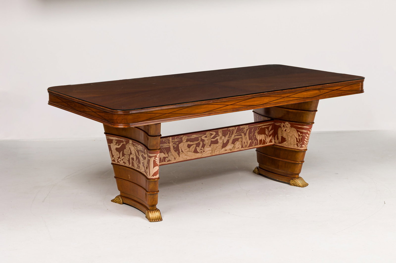 Vittorio Dassi attrib., Italian Art Deco refectory table: c. 1930s, Italy, the rectangular top with rounded corners, in chevron veneered figured mahogany, raised on trestle legs joined by stretcher decorated with a red and white lacquered bas-