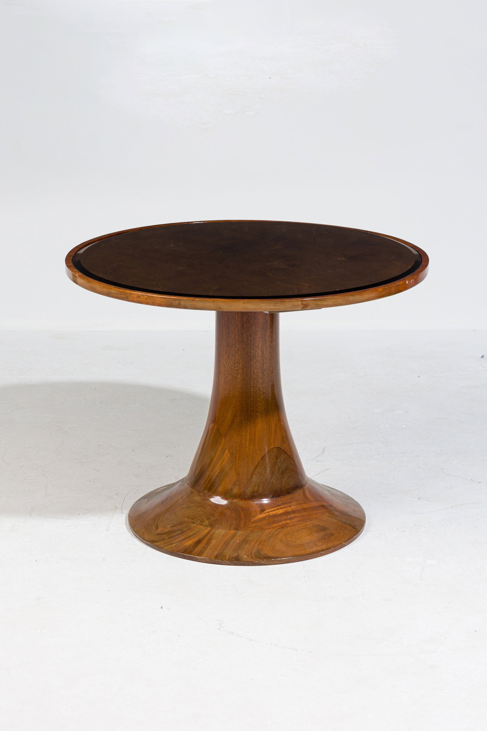 Italian Mid Century walnut pedestal occasional table: c. 1930s, Italy, laminated walnut jigsaw construction, the round top with inset clear glass, raised on hour-glass pedestal ending in spreading foot, 25"h x 31.5"dia Provenance: Property from