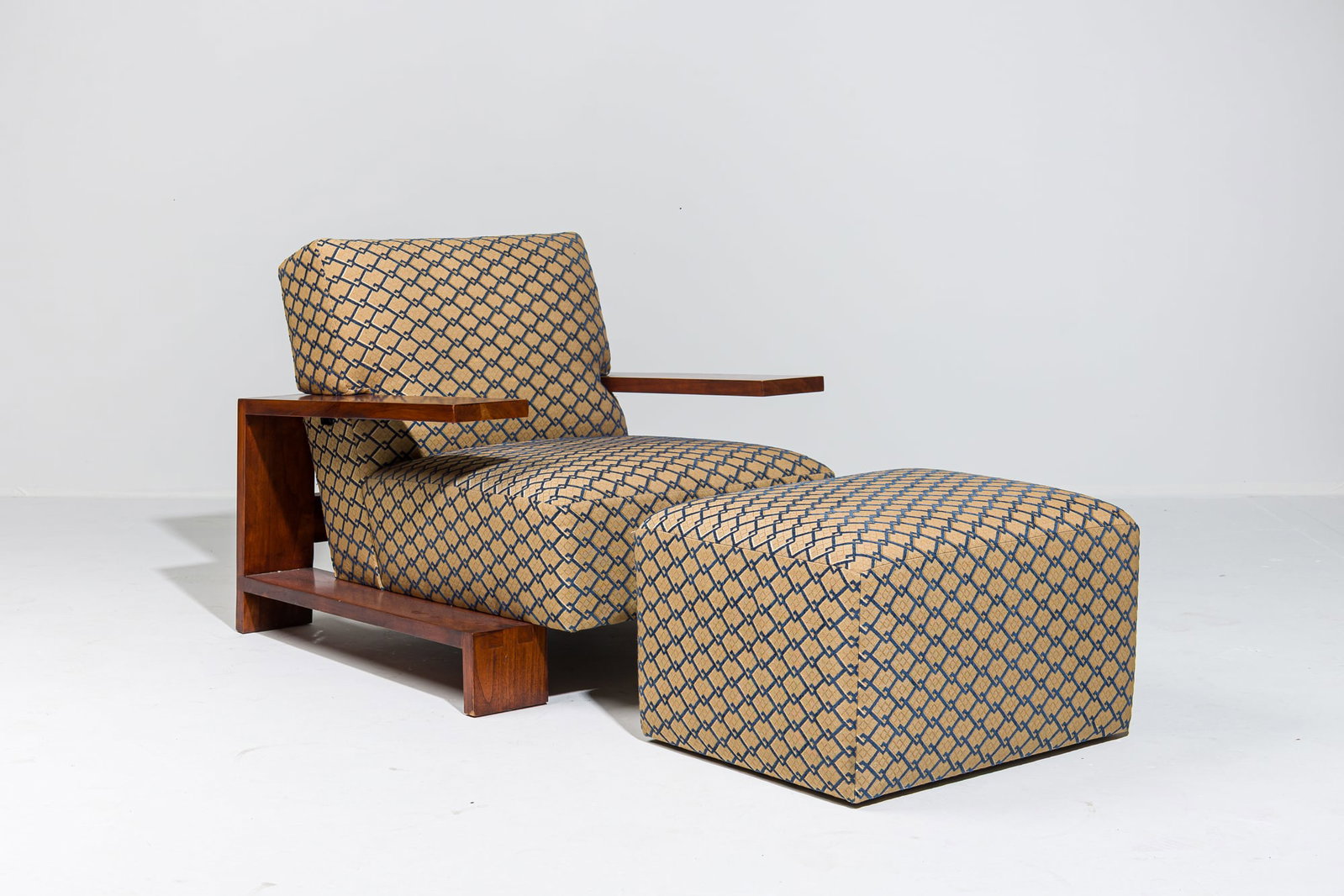 Thomas Moser, Edo lounge chair and ottoman: c. 2008, USA, solid Cherry wood frame, the wide plank cantilever arm dovetailed at the back, the back and seat upholstered in a blue and gold geometric damask, together with a simple cube poof raised 