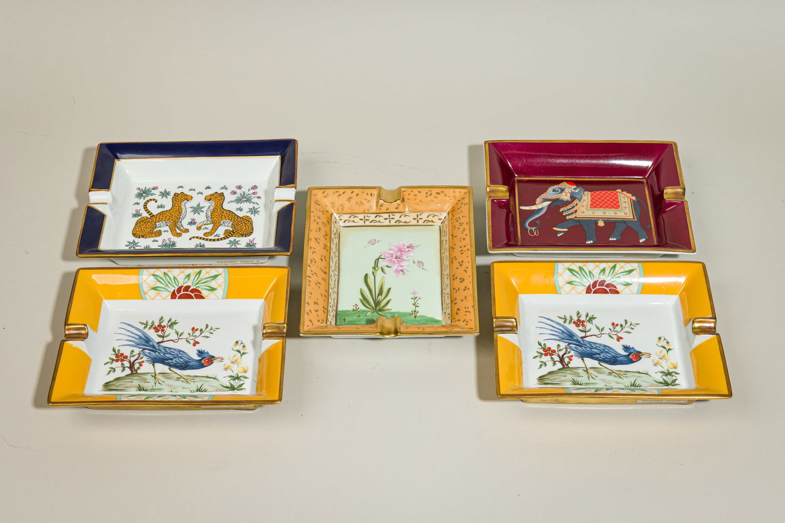 (5) Hermes porcelain cigar ashtrays: 20th c., France, gilt and polychrome enamels on. porcelain, including "Les Leopards", "Blue Bird", "Orchidee", and "L'elephant", each gilt signed, 1.5&