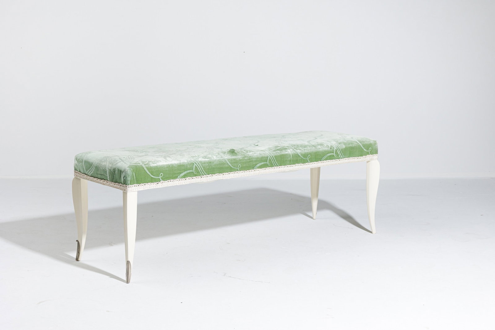 Stephen Bastone, custom Art Deco style velvet upholstered bench: 21st c., USA, white painted wood frame, the sculptural tapered legs ending in silver metal sabot, upholstered in a ribbon patterned lime green sculpted velvet with off-white 