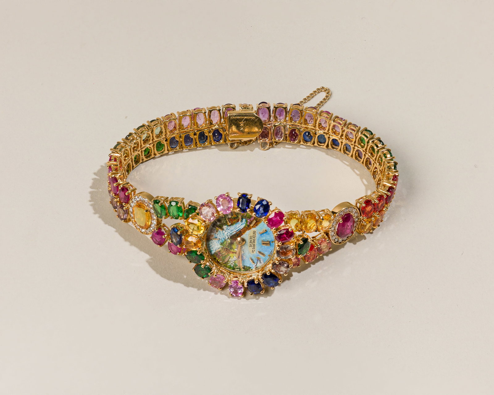 Patek Philippe Ladies Watch In 18K Gold With Color Gemstones: Type: Patek Philippe, C1960`s Case Material: 18K yellow gold Case Dimensions: 28 mm Dial: Hand painted landscape with applied hour markers Serial Number: 630906 Movement Number: 852195 Bracelet Materi