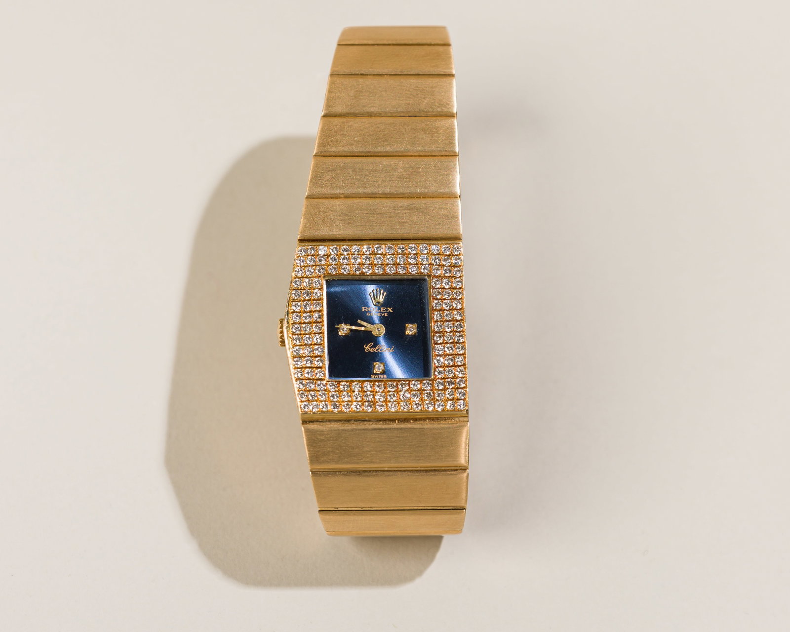 Rolex Queen Midas In 18K Yellow Gold: Type: Rolex,C`1976 Case Material: 18K yellow gold with pave set diamonds Case Dimensions: 24 mm wide x 23 mm top-to-bottom Dial: Sunburst blue dial with diamond hour marker at "3", '6