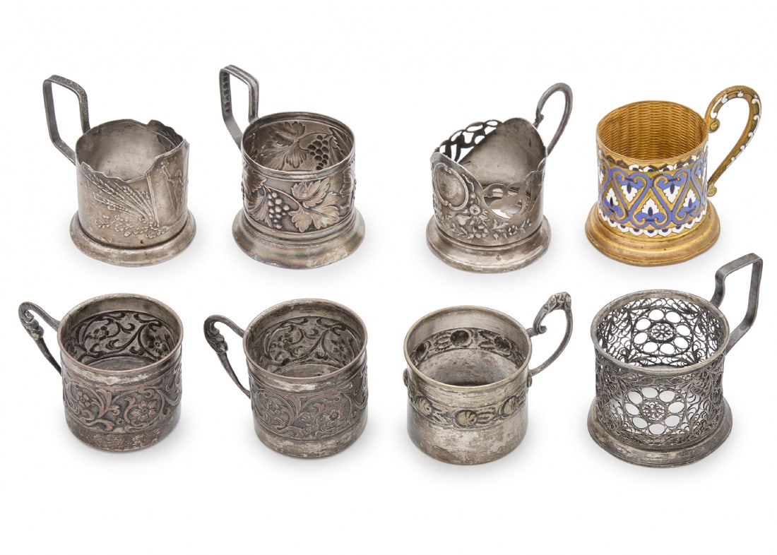 Eight Different Tea Glass Holders, Various Models and Manufacturers, Made of Silver-Plated Metal: Eight Different Tea Glass Holders, Various Models and Manufacturers, Made of Silver-Plated Metal, one decorated with enamel Some signed Width respectively: 9 to 11 cm Height respectively: 7.5 to 9 cm 