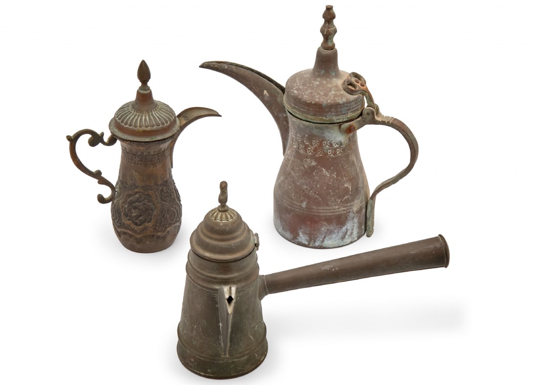Three Traditional Coffee Vessels Including a Dallah and Two Finjans: Three Traditional Coffee Vessels Including a Dallah and Two Finjans, made of metal, decorated with decorative engraving The Dallah is signed Height: 20-28 cm Notice: We are located in Israel and provi