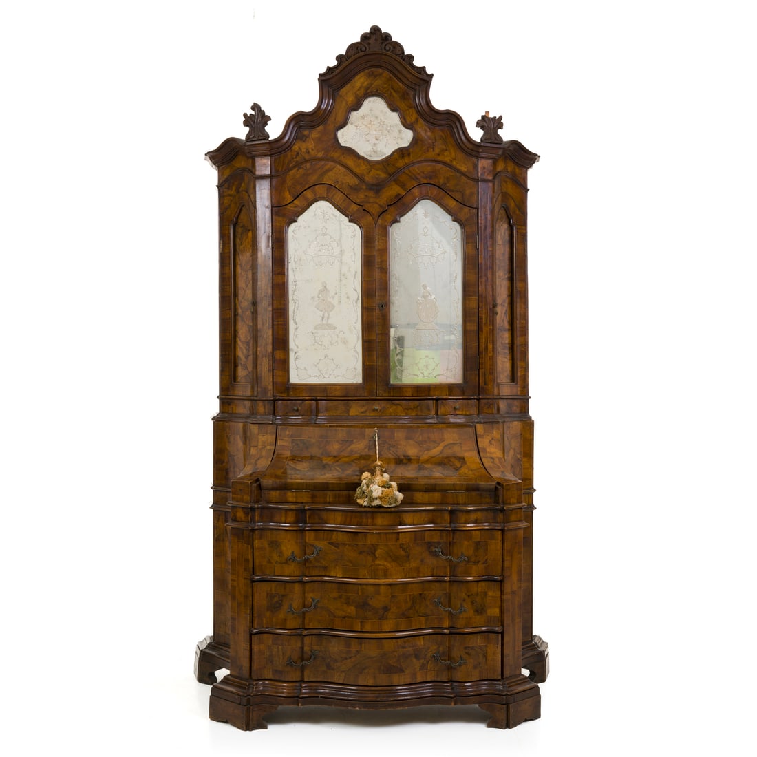 Trumeau, Italia, XX secolo: Trumeau lastronato Noce con fronte e fianchi mossi Italia, XX secolo 269 x 136 x 63 cm Parte superiore a due ante specchiate sormontate da riserva centrale e cimasa intagliata Parte inferiore con riba