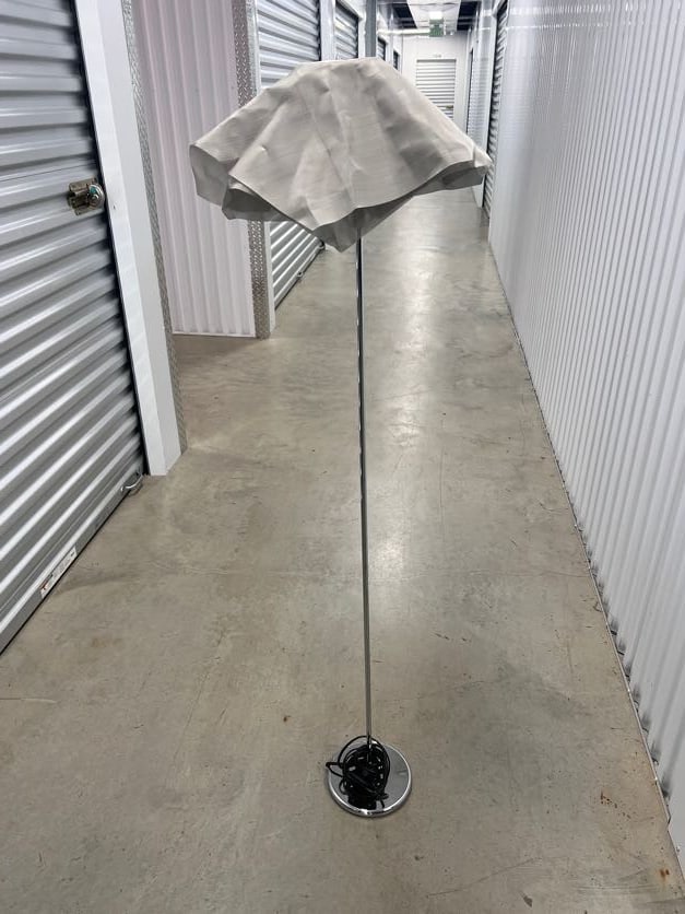 Modern Floor Lamp with Fabric Shade: A contemporary floor lamp featuring a sleek chrome base and a unique fabric shade. The lamp stands approximately 140 cm tall with a base diameter of 20 cm. The minimalist design complements various in