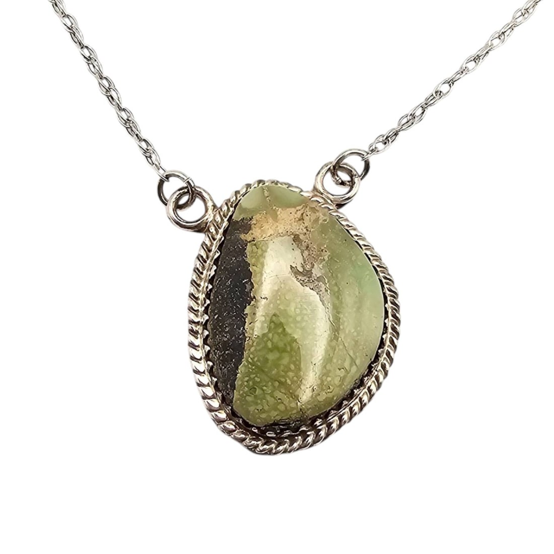 Annie Spencer Navajo Handmade Sterling Silver Kingman Turquoise Necklace: Handmade by Navajo artisan Annie Spencer, this necklace features a sterling silver chain with a Kingman turquoise stone pendant. The pendant is framed with a decorative rope-like edge and showcases na