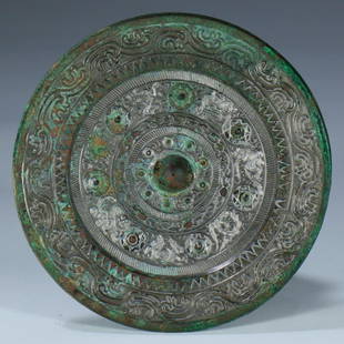 A Western Han Dynasty Bronze cast round mirror: A Western Han Dynasty (202 BC - 8 AD) Bronze cast round mirror, decorated with divine birds and beasts, with silver hot stamping on the protrusions.Provenance: I.K. Gallery AUS, a private collector