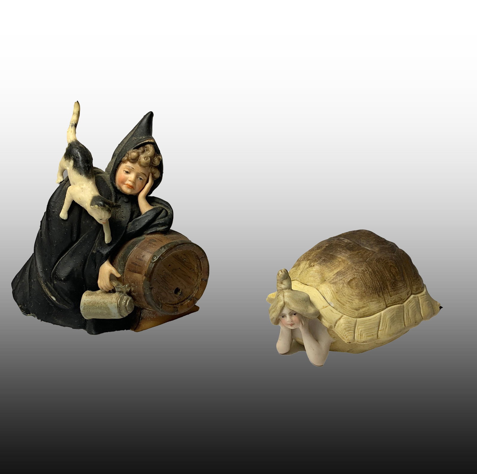 Shafer & Vater Porcelain Figures: A lot of two porcelain figurines by Shafer & Vater Co. One figure is of a witch type girl, and the other of a turtle girl. The top of the turtle comes off and reveals a nude within. They measure 4 1/2