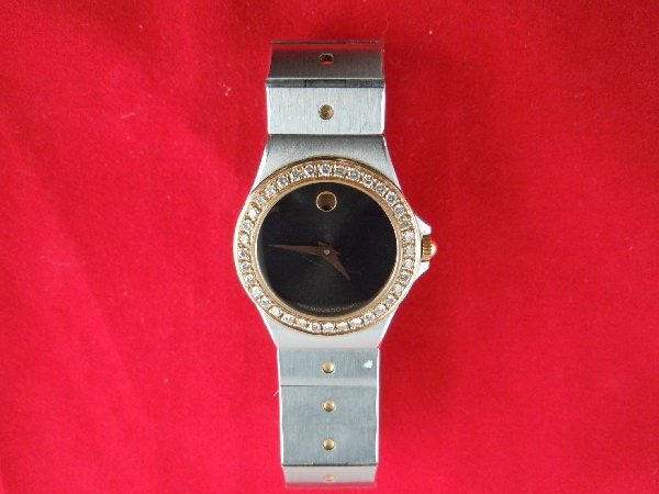 Movado Stainless Steel Watch with Diamond Bezel: The black circular dial is surrounded by diamonds and has a stainless steel band.