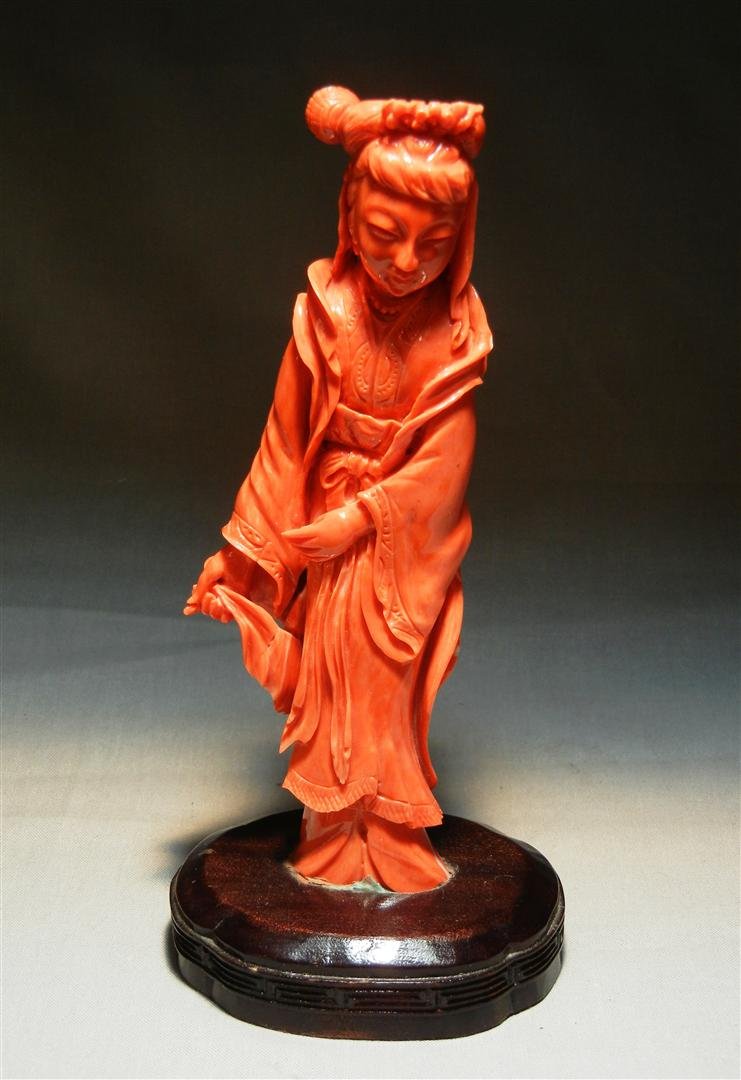 19thc. Female Coral Figure: 19th century coral figurine depicting a female holding a sash on a wooden base with minor coloration to white. Coral measures 6 1/2" without stand.