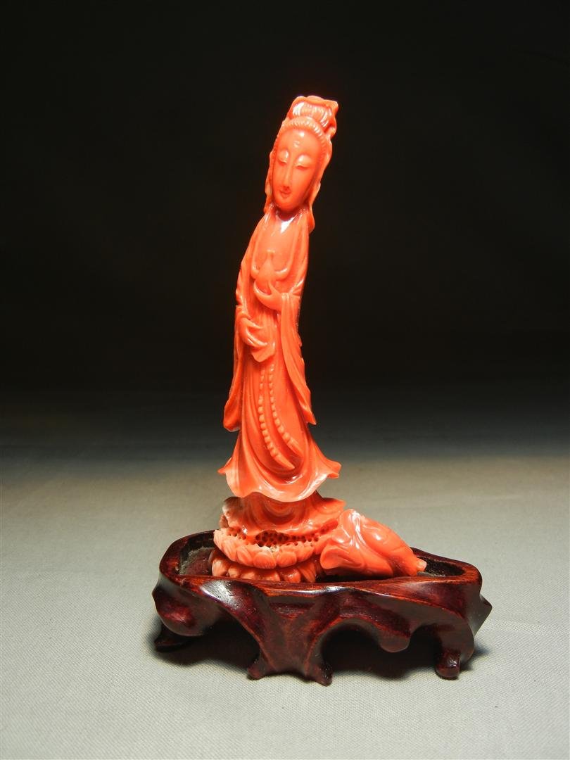 19thc. Blood Coral Quanyin: 19th century blood coral carved Quanyin with minor discoloration to white at the bottom. Figure affixed to teakwood stand and measures 3 1/2"H (without stand)