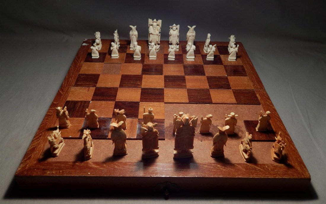 Chinese Ivory Chess Set: Chinese ivory chess set with natural and tinted figures within a fitted wooded case folding out to a playing board.