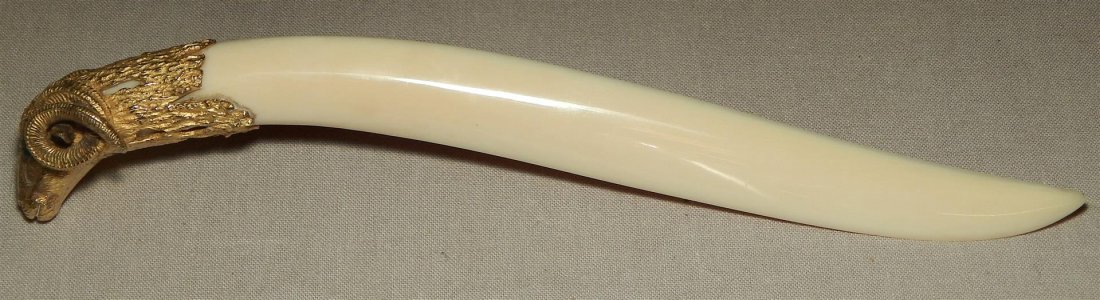 Cartier Gilt Silver & Ivory Letter Opener: A Cartier gilt silver and ivory rams head letter opener with emerald eyes measuring 8" long. The ram's head has "Cartier" impressed on neck (see photo).