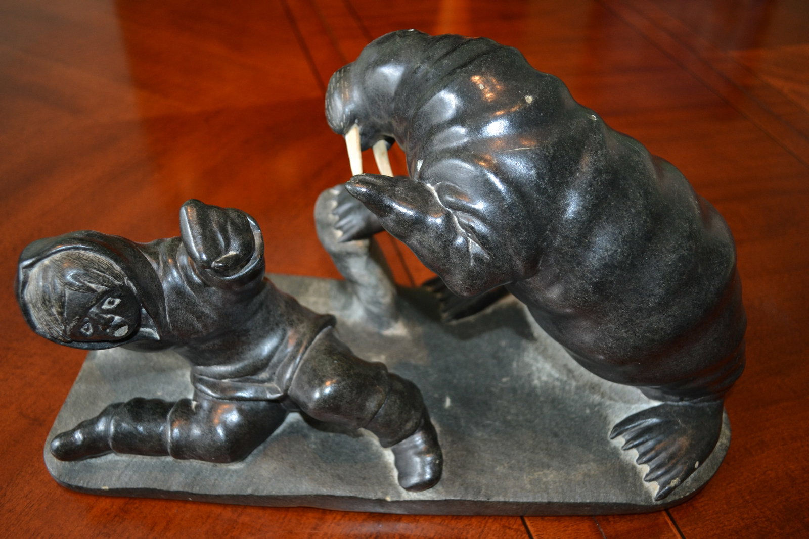 Inuit Sculpture Levi Alasuak of Walrus & Hunter: Inuit Sculpture of Large Walrus attacking a Hunter Inuit Carved stone sculpture Signed by Levi Alasuak. Inuit, Akulivik, (b. 1951) carved stone, signed along with the Canada eskimo art esquimau label 