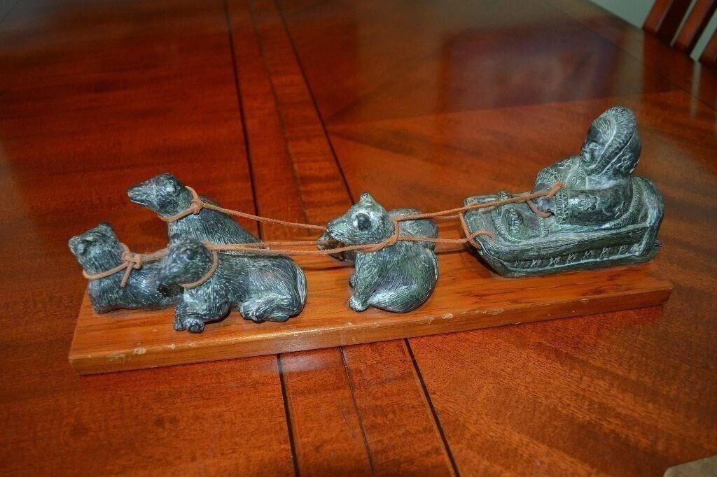 Vintage Wolf Cast Woman on Dog Team Wood Board: Vintage Wolf Cast Inuit Woman and Dog Team. Mounted on Wood Board. A non-inuit sculpture. Souvenir Item purchased in 1975 The leather straps are original. In Fine condition, overall Minor chips on woo