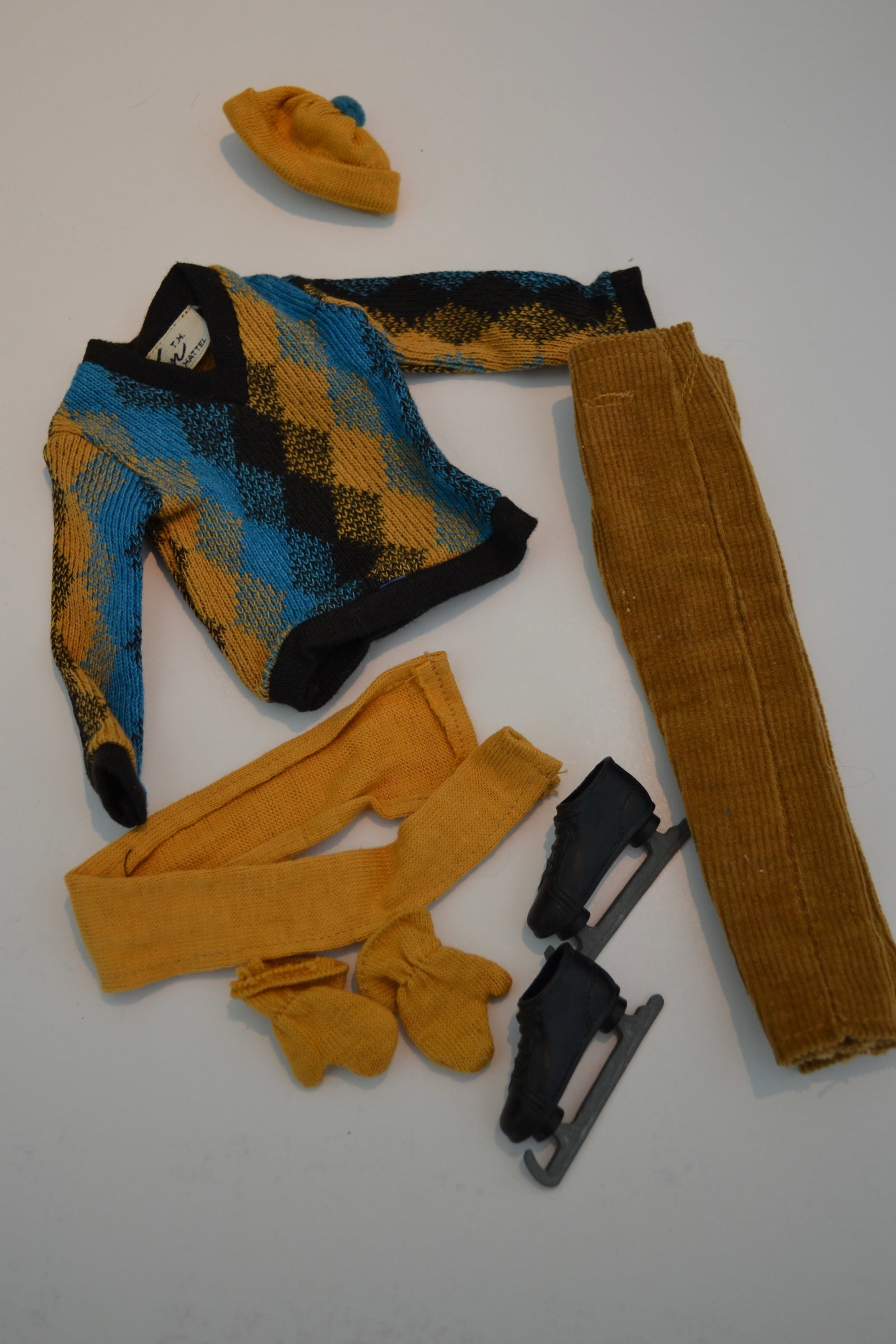 1964 Mattel Ken Fun on Ice Outfit #0791 Ensemble: Mattel Ken Fun on Ice Outfit #0791 Ensemble Ken takes Barbie ice skating in handsome blue and gold argyle sweater, gold corduroy trousers, matching stocking cap and scarf and mittens. includes shoe ra