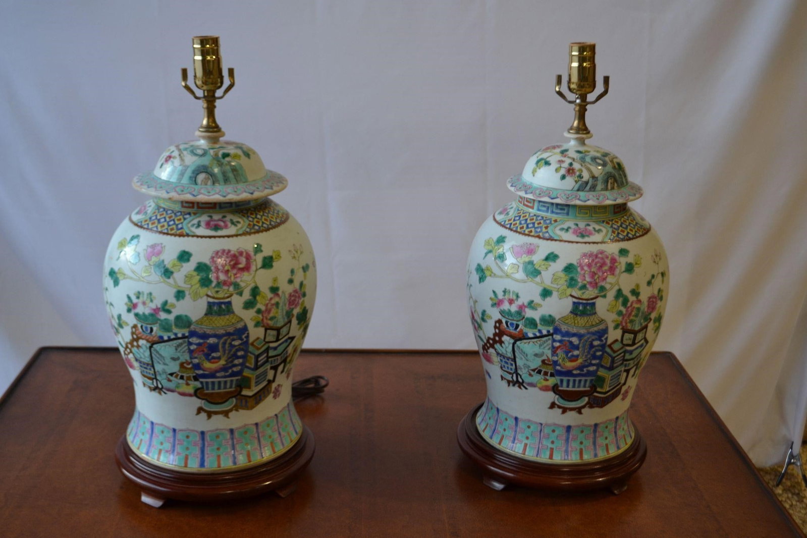 VTG PR PORCELAIN CHINESE COVERED GINGER JAR LAMPS: VINTAGE PAIR PORCELAIN CHINESE COVERED GINGER JAR AS LAMPS Handmade in China, this jar is a testament to the rich cultural heritage of Chinese art features intricate floral designs in the classic fami