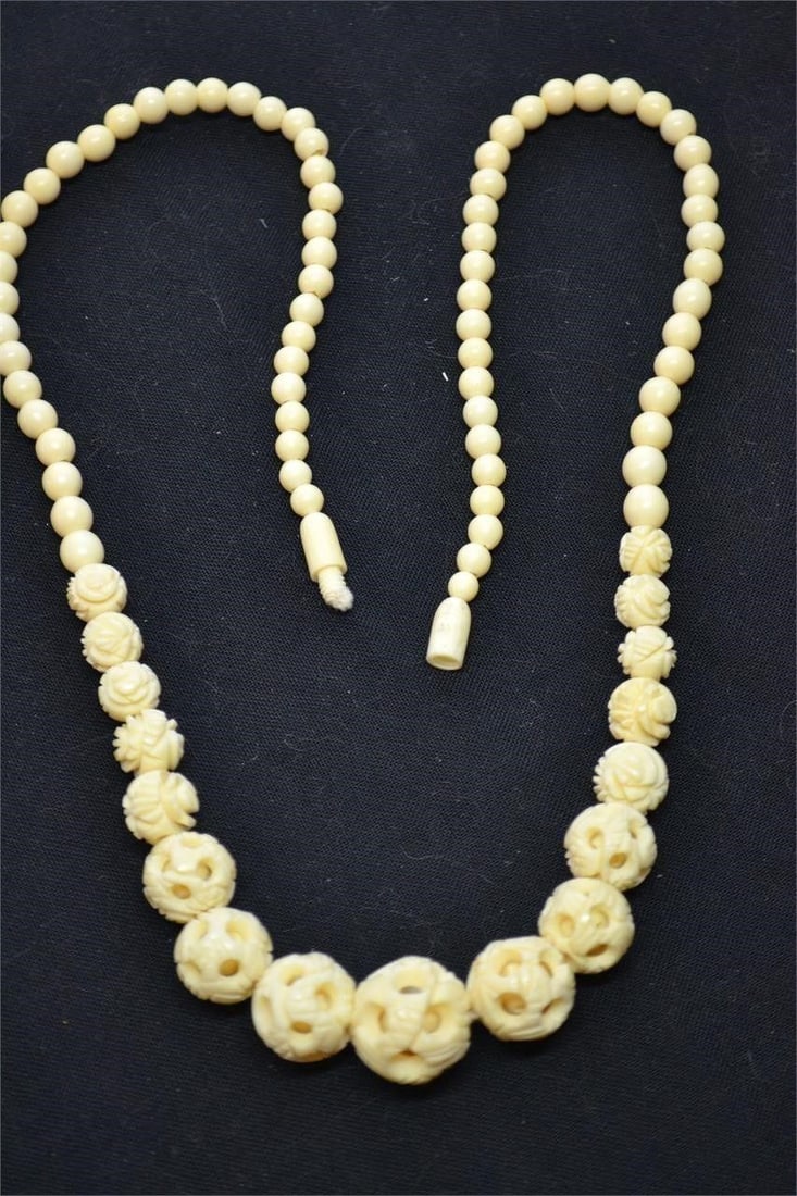 Vintage graduated carved bone beaded necklace: Vintage graduated carved bone beaded necklace, featuring intricate rose designs or "ball-in-a-ball" openwork techniques. Carved bovine bone, often featuring an aged, ivory-like appearance. Graduated b
