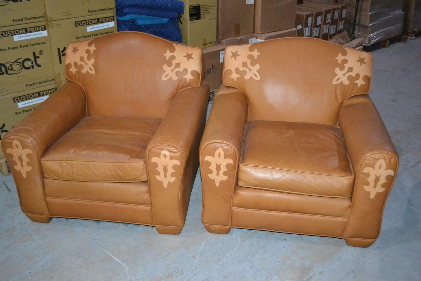 LENORE MULLIGAN DESIGNS (2) LEATHER CHAIRS: LENORE MULLIGAN DESIGNS (2) LEATHER CHAIRS TAN WESTERN STYLE FLEUR DE LIS Designers come see!Cowboy Collection resembles a wolf in center at arms and star on corners of chair back. Leather welt on