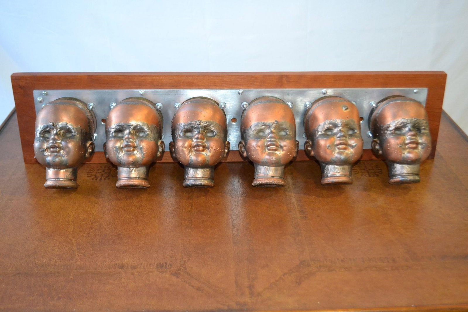 COPPER DOLL HEAD MOLDS ON STEEL MOUNTED ON WOOD: COPPER DOLL HEAD MOLDS ON STEEL (6) MOUNTED ON WOOD Extremely RareDating from the 1920s, the doll presumably is an iconic French toy that was well-loved and collected by children of the period. This m