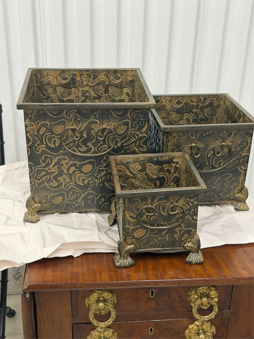 Set of three Metal Footed Containers: Set of three metal planters or Waste Containers features an antique bronze-colored, embossed floral pattern and elevated legs Measurements 10" x 10" x 10"8" x 8" x 8"6" x 6" x 6"