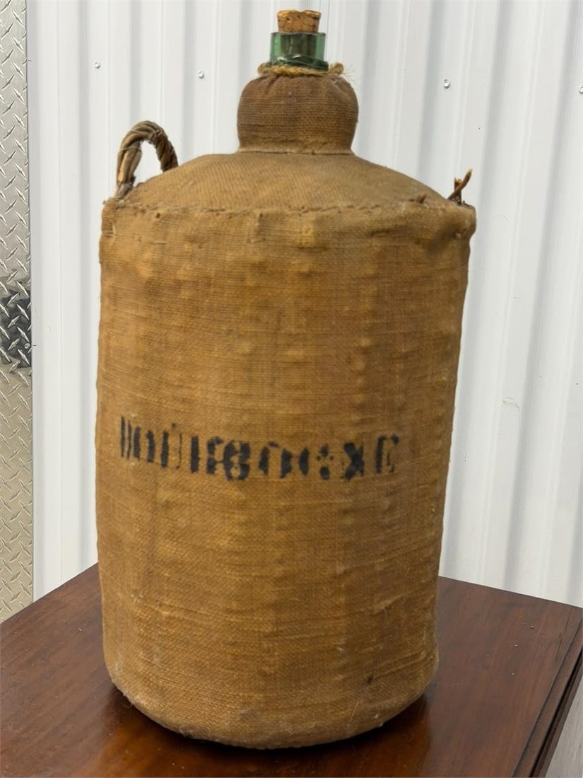Vintage French Demijohn Bottle with Woven Burlap: Vintage French demijohn bottle, a large, narrow-necked glass vessel typically used for storing liquids like wine or brandy. The bottle is made of green glass and encased in a woven hessian or burlap