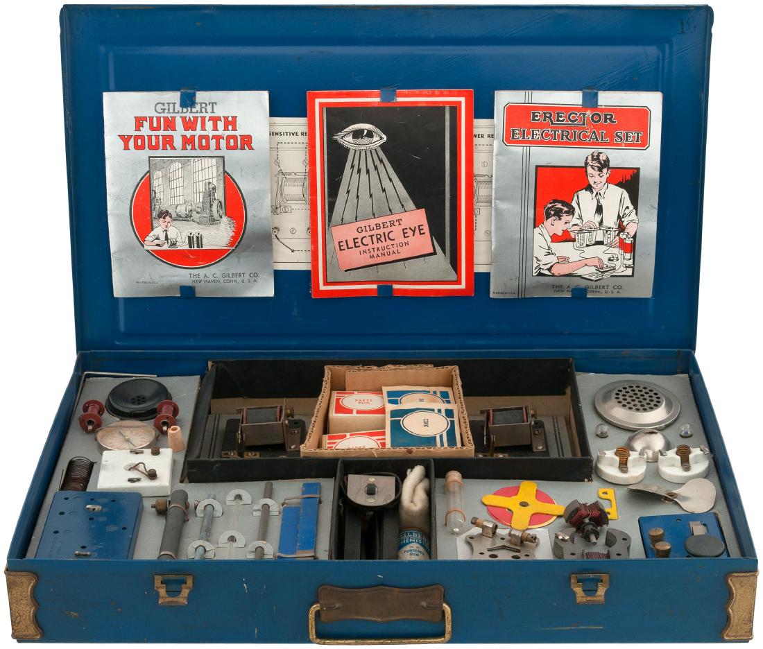"GILBERT ELECTRICAL SET/ELECTRIC EYE" BOXED 1930s SET.: 12.25x20.25x2-7/8" deep painted metal case contains A.C. Gilbert Co. set No. 10, 1930s . Lid has metal fasteners and features illustrated label featuring boy using the "Gilbert Electric Eye." Case has