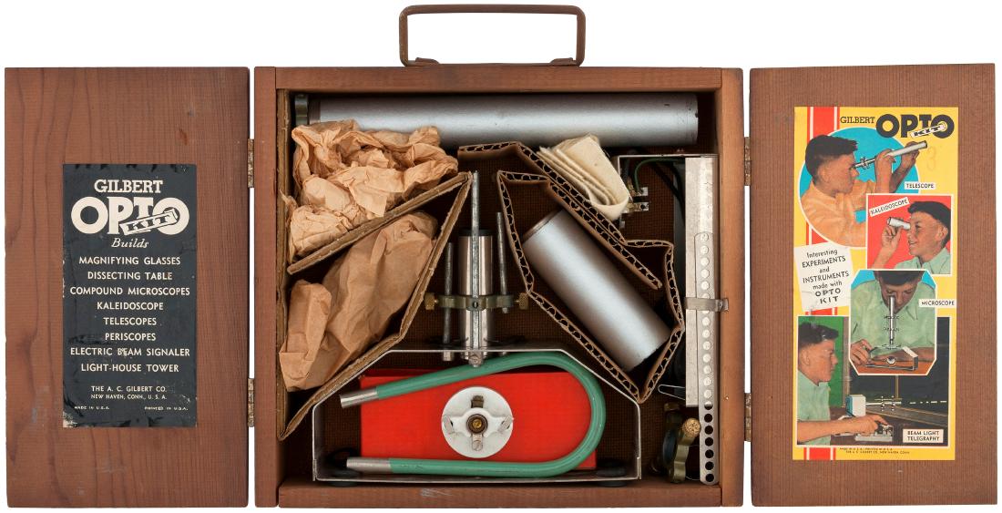 "GILBERT OPTO KIT" BOXED 1930 SET.: 8-7/8x10x2.5" deep wooden case contains A.C. Gilbert Co. set, 1930. Case's bi fold lid has metal "Gilbert" plate/fastener, which shows aging/oxidation. Case is Fine overall. Undersides of lid have lab