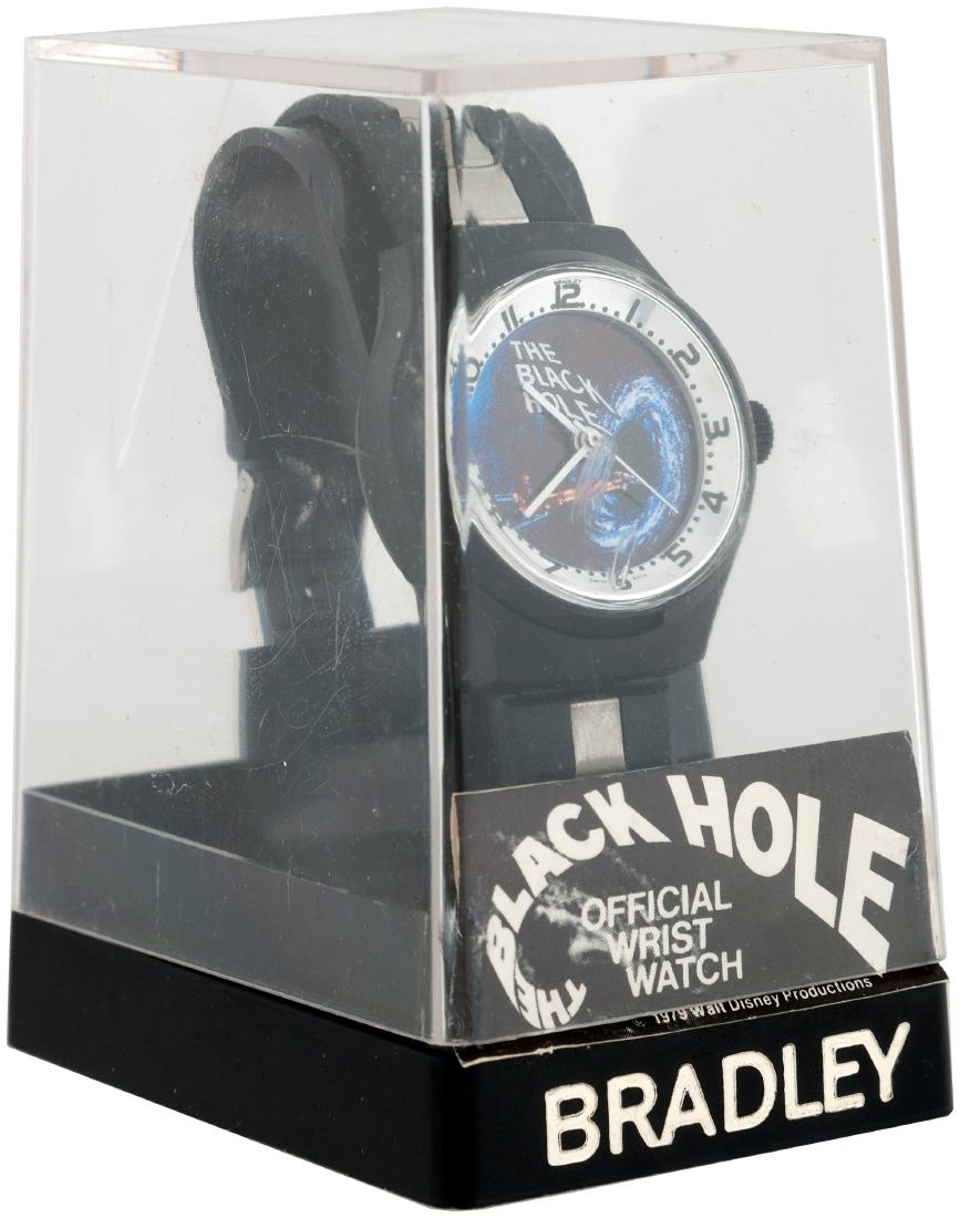 "THE BLACK HOLE" BRADLEY WATCH IN CASE.: 2-1/8x3x3-1/8" tall plastic case w/clear case lid contains watch w/1.25x1.5" plastic case watch w/vinyl band w/silvered metal accents. Dial features image of USS Cygnus approaching a black hole. Bradl