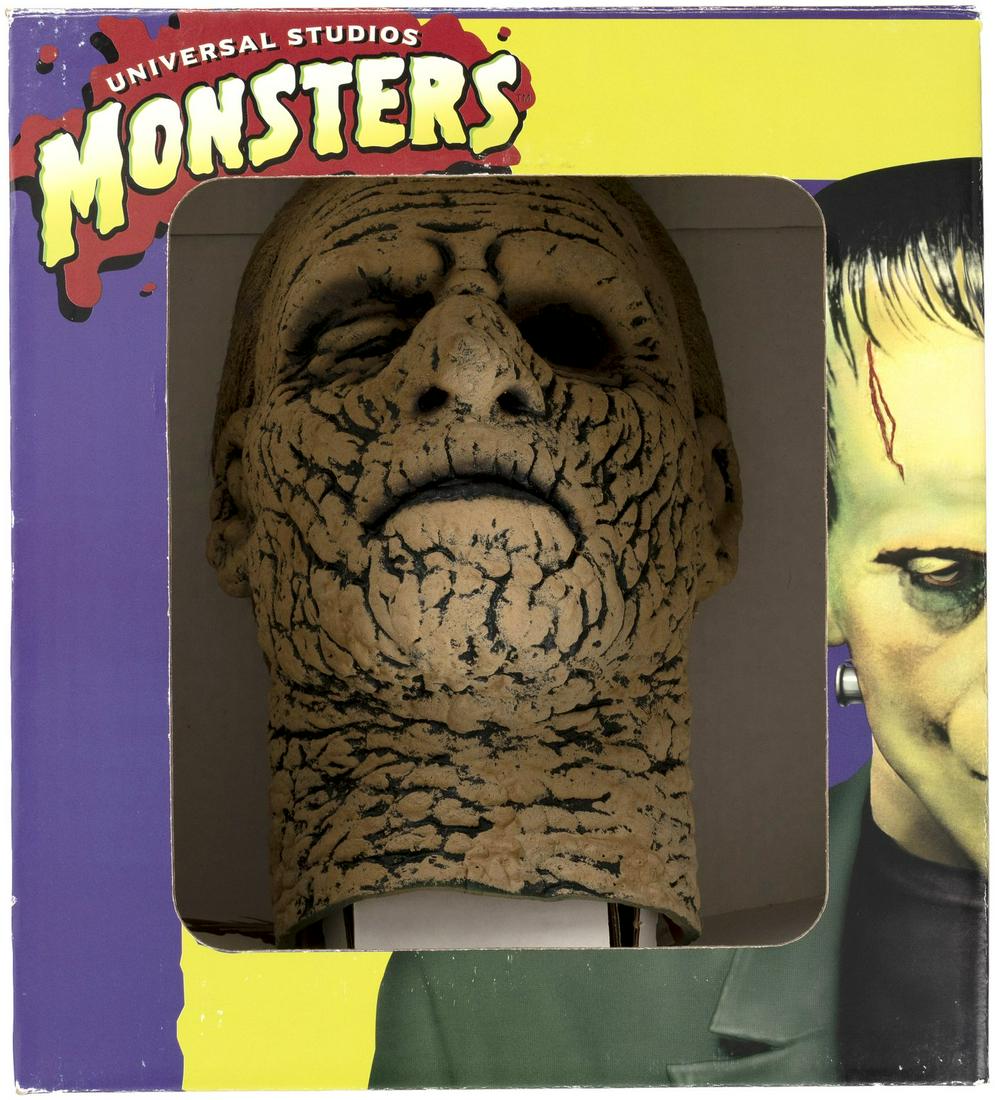 DON POST STUDIOS "UNIVERSAL STUDIOS MONSTERS" THE MUMMY (CHANEY, VERSION B) BOXED LATEX MASK.: 12-1/8x12-1/8x12-1/8x13.5" tall open display box contains full latex mask by noted maskmaker Don Post Studios, 1997. This is the Lon "Chaney Version B" of The Mummy mask, featuring a style more remini