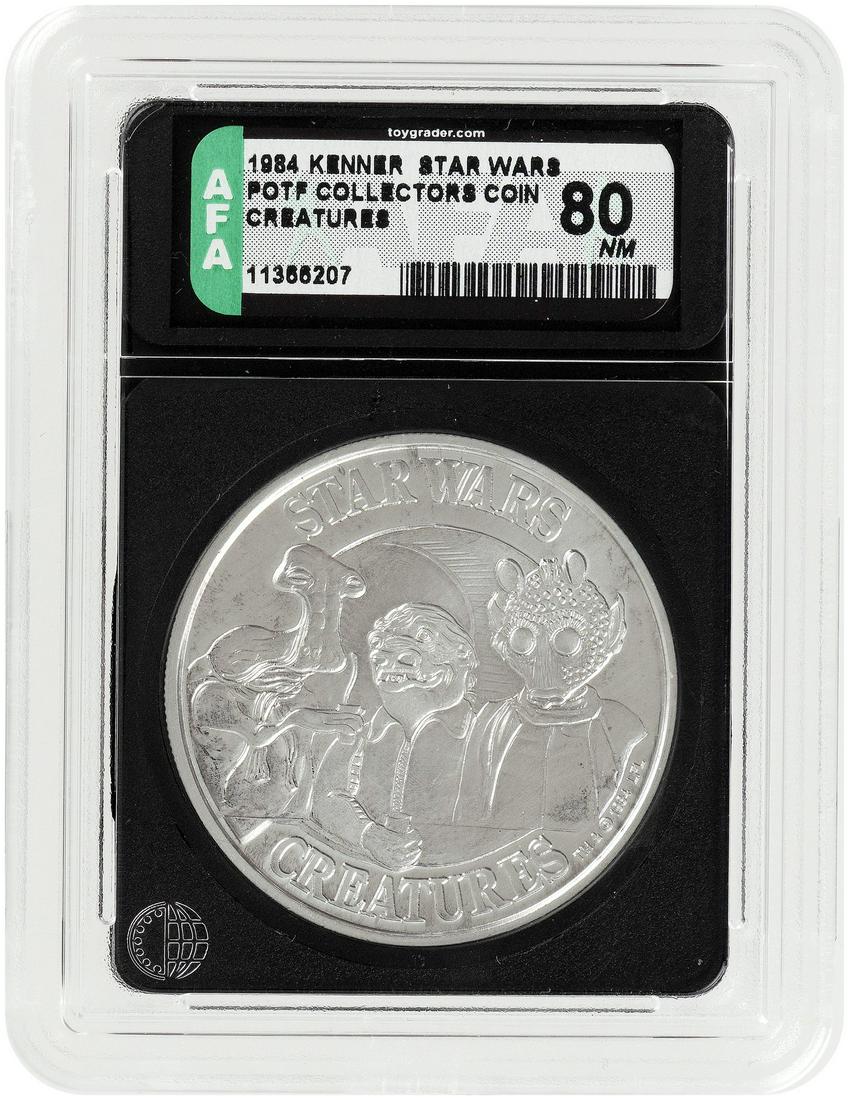 KENNER STAR WARS: THE POWER OF THE FORCE (1984) - COLLECTORS COIN CREATURES AFA 80 NM.: AFA graded and encapsulated Power Of The Force (POTF) Collectors Coin. "Creatures/May The Force Be With You" reverse. Coin shows Cantina aliens Hammerhead, Snaggletooth and Greedo. Mail-away exclusive